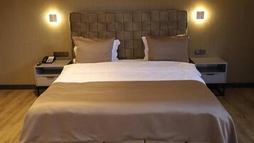 A neatly made bed with a tufted headboard, two bedside tables with lamps, and a wooden floor.