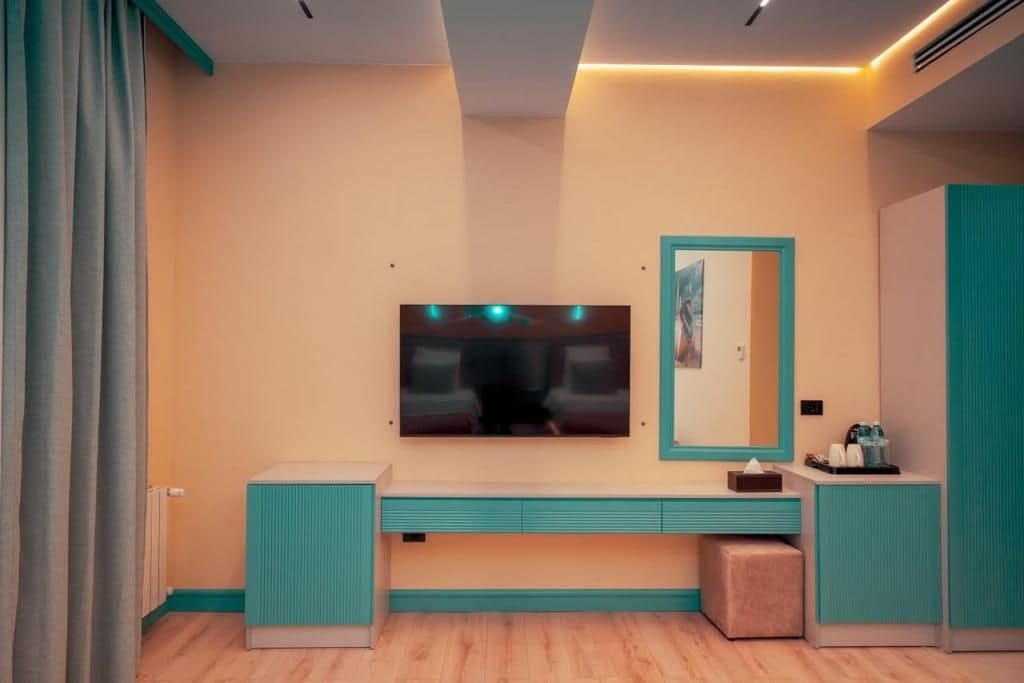 A modern bathroom with a large mirror, a vanity with a sink, and a television mounted on the wall.