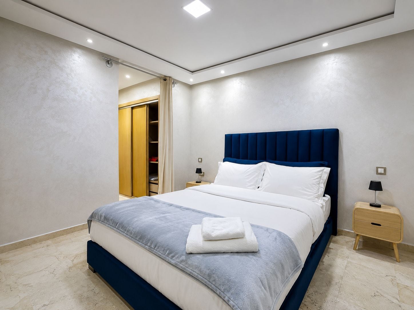 Un dormitorio moderno con cama, mesitas de noche, un armario y la puerta del baño.