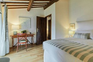 A bedroom with a bed, a desk with a chair, a door, and a window with curtains. - Apartment with terrace over Umbrian countryside (Gubbio)