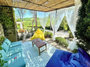 An outdoor seating area with a table and chairs, a yellow cushion, and a view of a garden. - Apartment with terrace over Umbrian countryside (Gubbio)