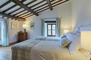 A bedroom with a large bed, two bedside tables, a window with curtains, and a wooden ceiling. - Apartment with terrace over Umbrian countryside (Gubbio)