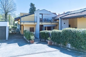 A two-story house with a balcony, a garage, and a well-maintained garden.