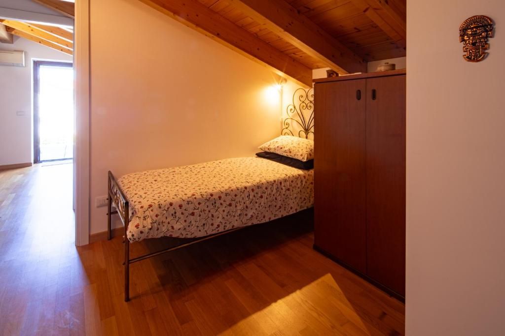 Un dormitorio pequeño con una cama individual, armario de madera y techo inclinado.