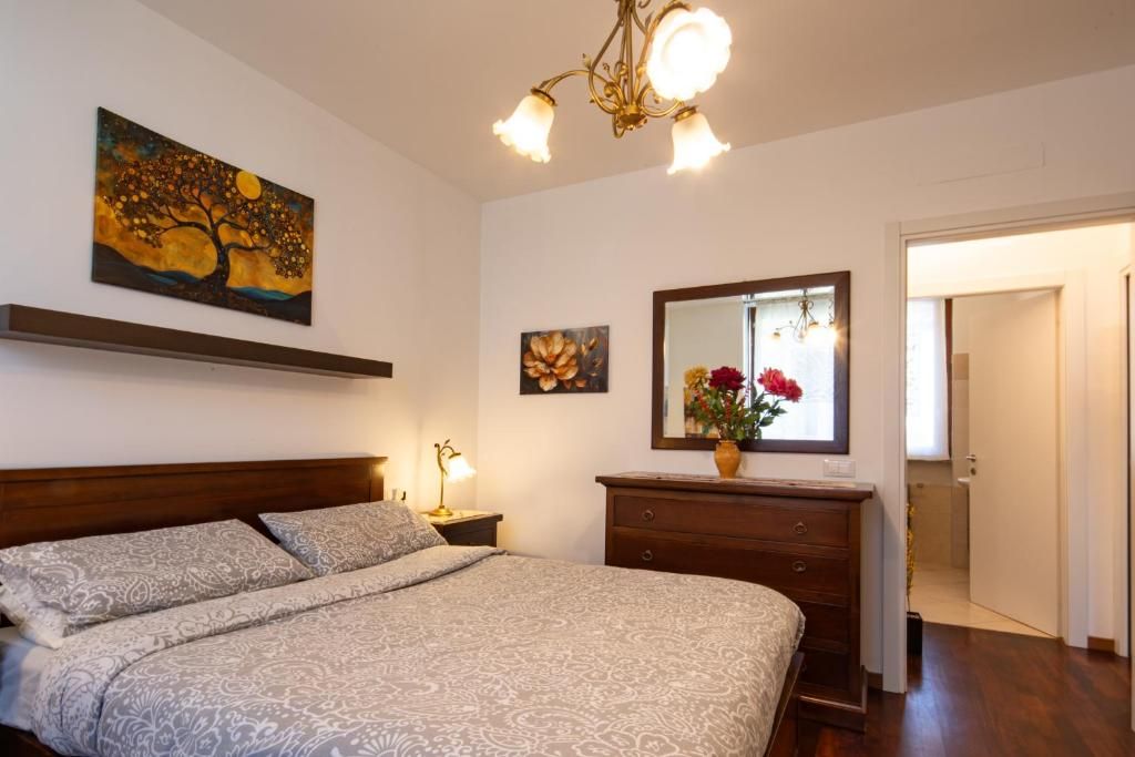 Una camera da letto con un letto, un comodino, una cassettiera, uno specchio e opere d'arte alle pareti.