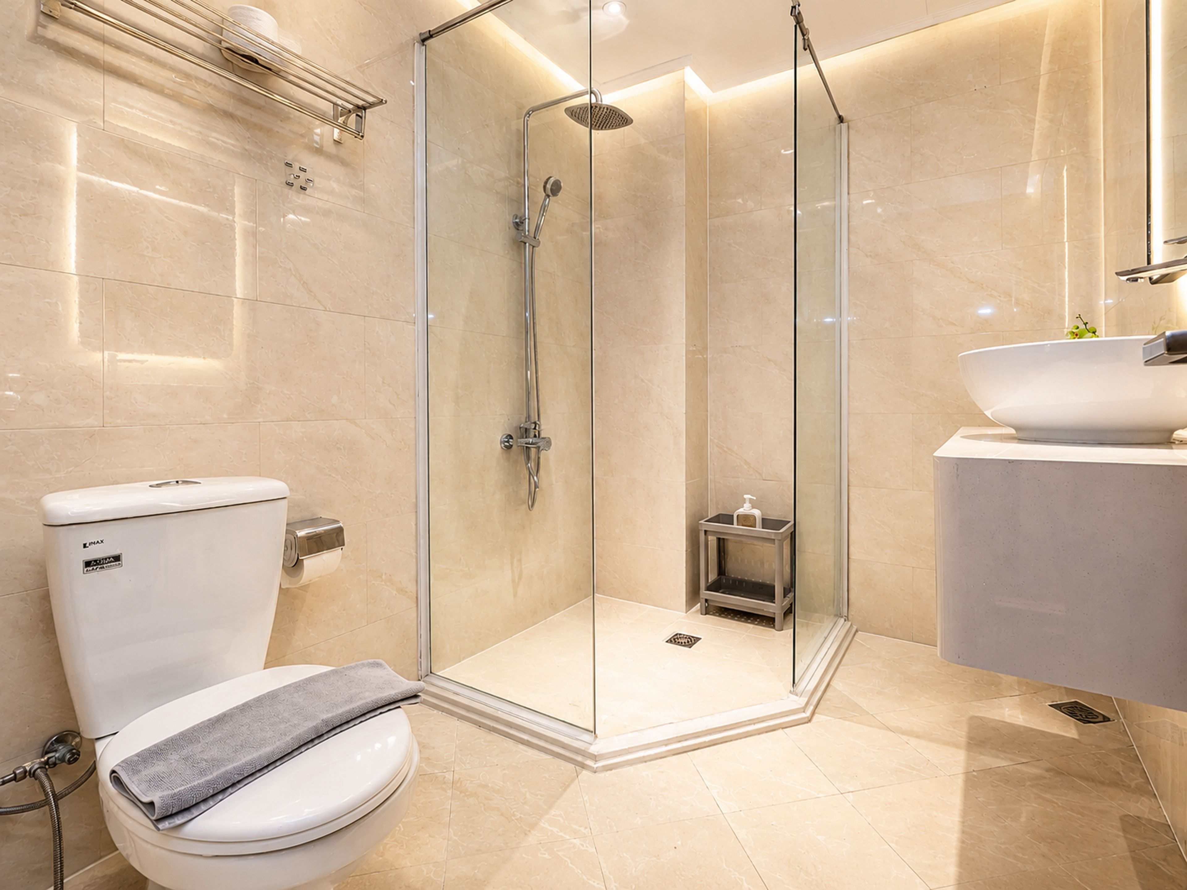 Ein modernes Badezimmer mit einer gläsernen Duschkabine, Toilette und Waschbecken mit großzügigem Becken.