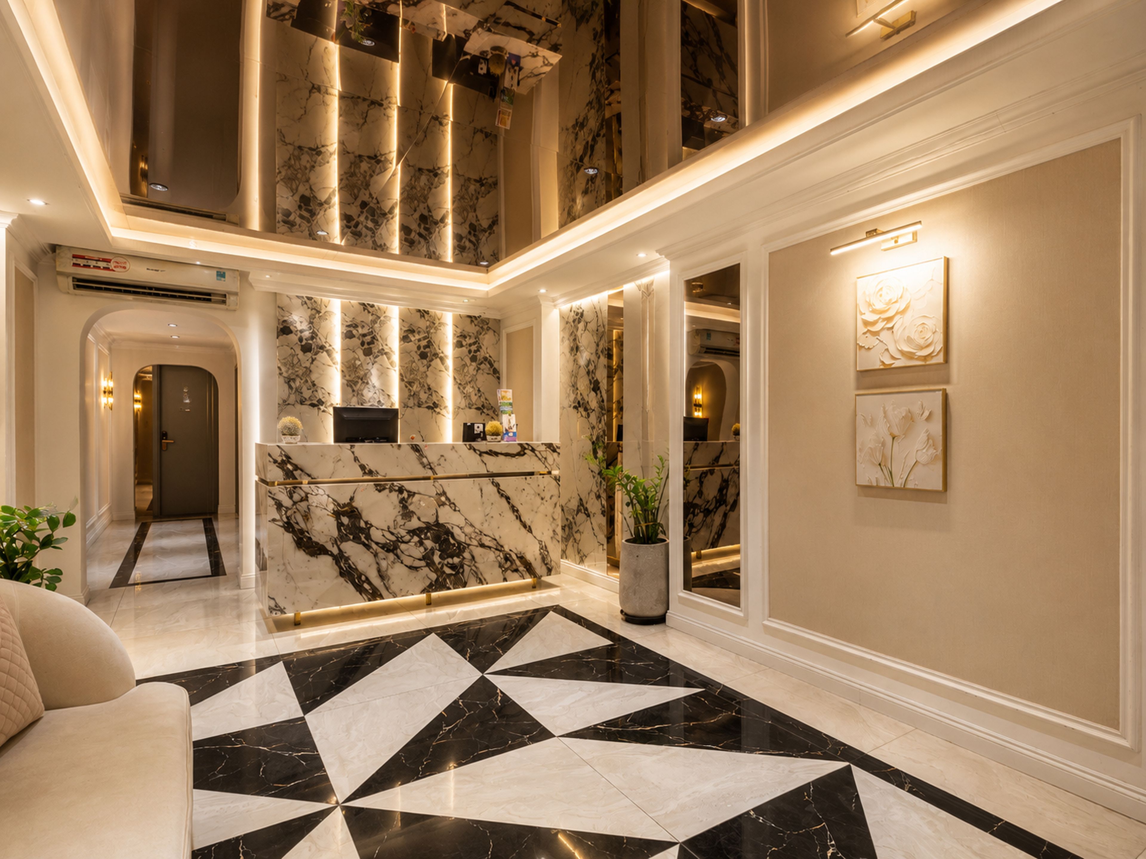 Eine Hotelhalle mit einem geometrisch gemusterten schwarzen und weißen Marmorboden, einer Rezeption und einer Zimmerpflanze.