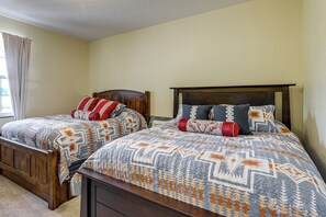 A double bed with a patterned bedspread and two pillows, a wooden headboard, and a window with curtains. - Mtn-View Ranch Near Black Canyon Nat'l Park (Crawford)