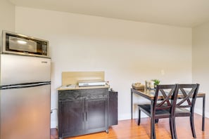 Una cocina compacta con microondas integrado, un refrigerador y un mueble de madera con encimera.