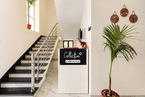 Una escalera con barandilla, un cartel que dice 'Collection OYO-Serviced' y una planta en maceta.