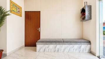 Un vestíbulo moderno y limpio con una puerta de madera, un banco con base de mármol y una pared de vidrio con estante.
