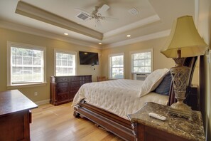 A bedroom with a bed, dresser, TV, and a lamp. - 1 Block to Beach! Elegant Family Home in Gulfport (Gulfport)