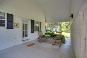 Eine überdachte Veranda mit Tisch und Stühlen, einer Tür und einem Fenster mit Fensterläden.
