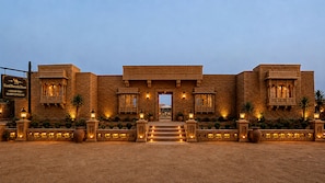 Un resort en el desierto con fachada de piedra, un letrero y una entrada bien iluminada.