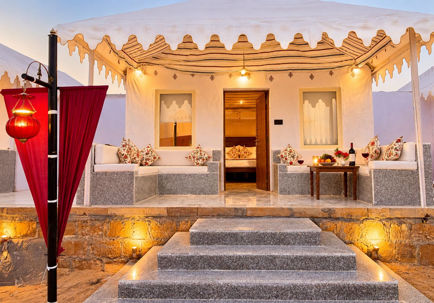 Habitación de hotel con cama, zona de estar y mesa de comedor con vela y fruta.