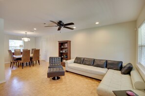 A living room with a sofa, ottoman, and a dining area with chairs and a table.
