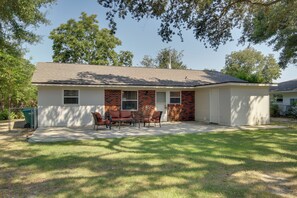 A single-story house with a covered patio area, a brick exterior, and a lawn.