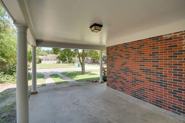 A covered outdoor area with a brick wall and a concrete floor.