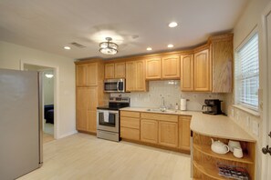Cocina con armarios de madera, electrodomésticos de acero inoxidable, horno empotrado y cafetera.