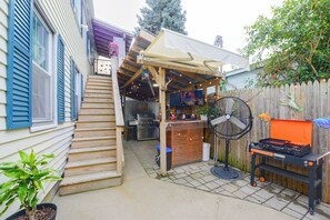 A backyard with a barbecue area, a fan, and a TV screen. - Walk to MBTA Station! Gloucester Extended Stay (Gloucester)