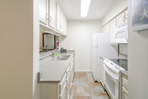A compact kitchen with white cabinets, a double sink, a stove, and a microwave. - Resort Perks! Lakefront Unit | Extended Stays (Hot Springs)