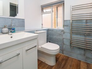 Ein Badezimmer mit einem weißen Waschbecken, einer Toilette und einem Fenster.
