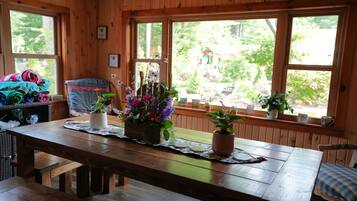 Un interior de madera con una mesa de comedor, bancos y plantas en macetas.