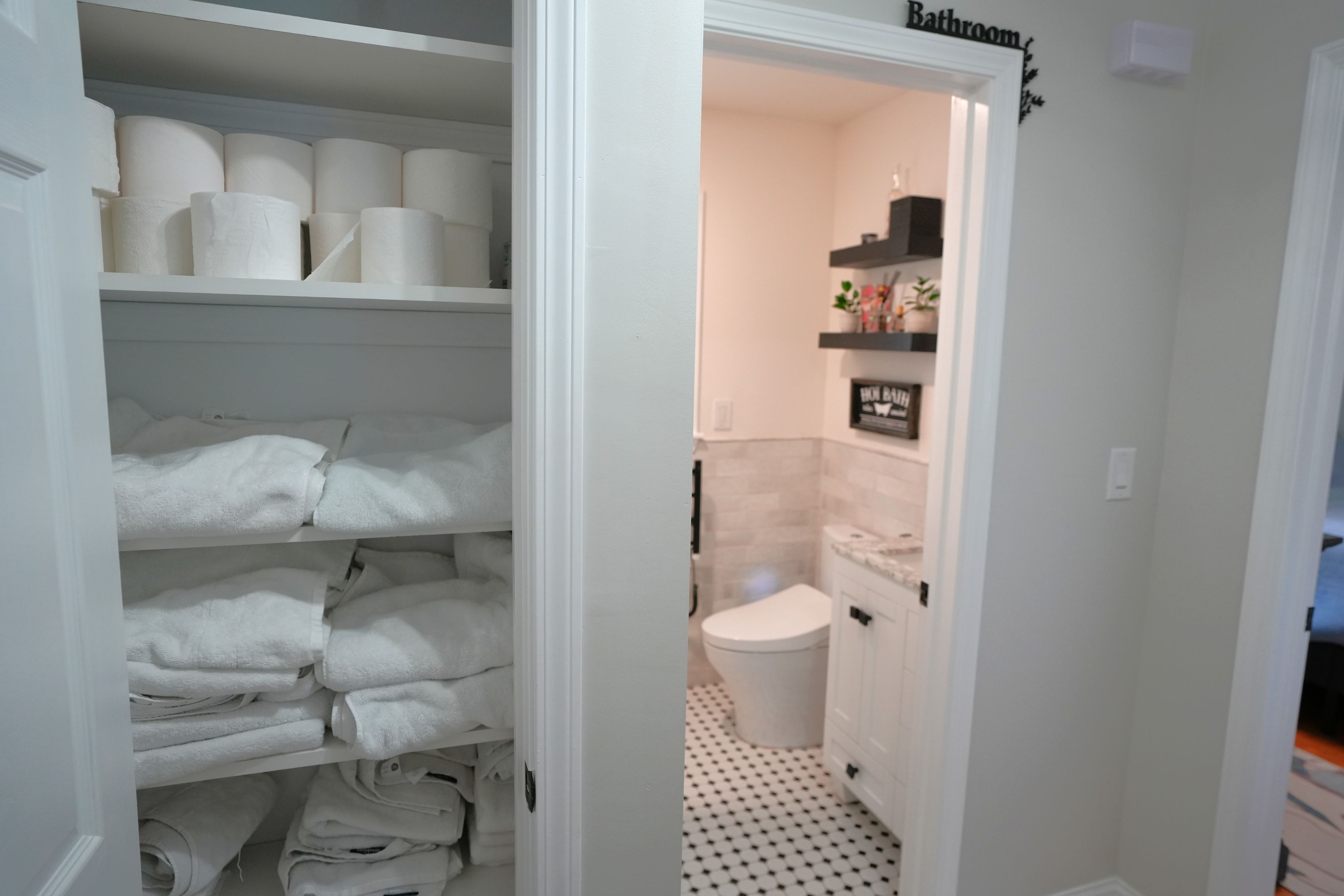 A bathroom with a toilet, a shelf with toiletries, and a sign that reads 'Bathroom'.