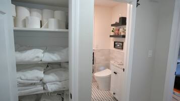 A bathroom with a toilet, a shelf with toiletries, and a sign that reads 'Bathroom'.
