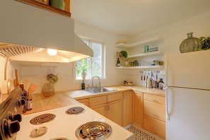 A modern kitchen with a gas stove, a sink, wooden cabinets, and a refrigerator. - Quiet Neighborhood, Home Office & Fenced Yard! (Portland)