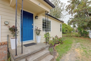 A house with a blue door, a small porch with steps, and a garden with various plants. - Quiet Neighborhood, Home Office & Fenced Yard! (Portland)