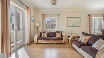 Un salon spacieux avec deux canapés, une table basse et une lampe.