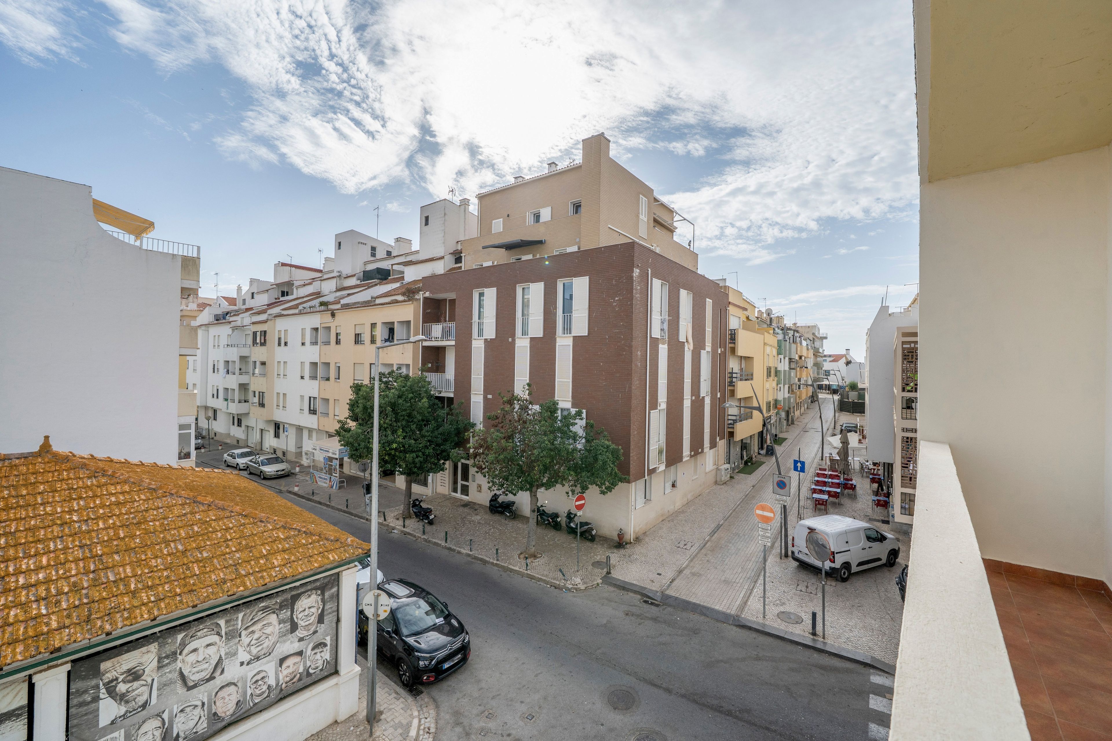 Vista de la calle con edificios, coches estacionados y cielo despejado.