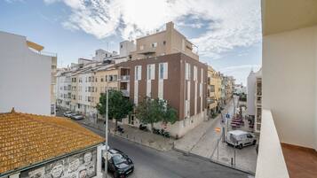 Vista de la calle con edificios, coches estacionados y cielo despejado.