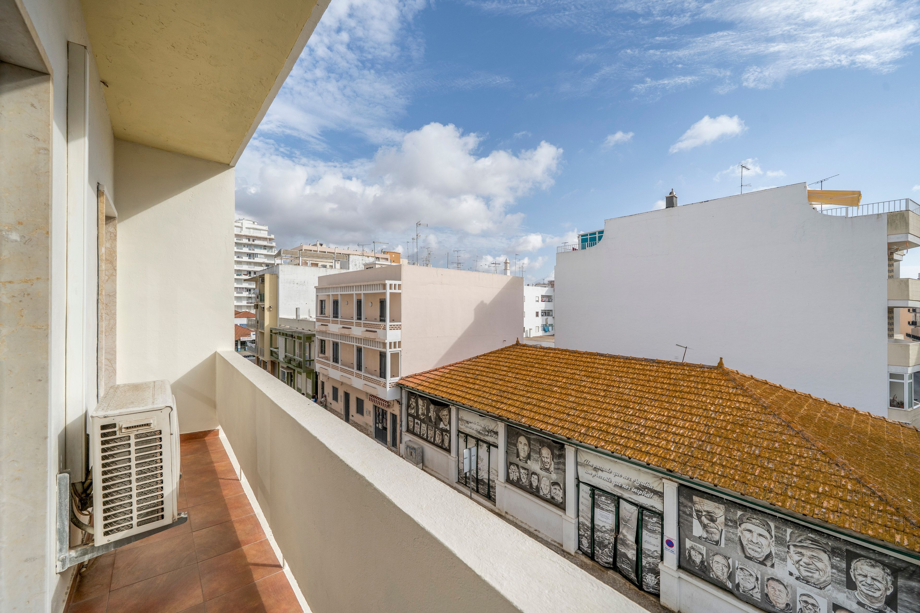 Un balcón con techo de tejas que da a una calle con edificios.