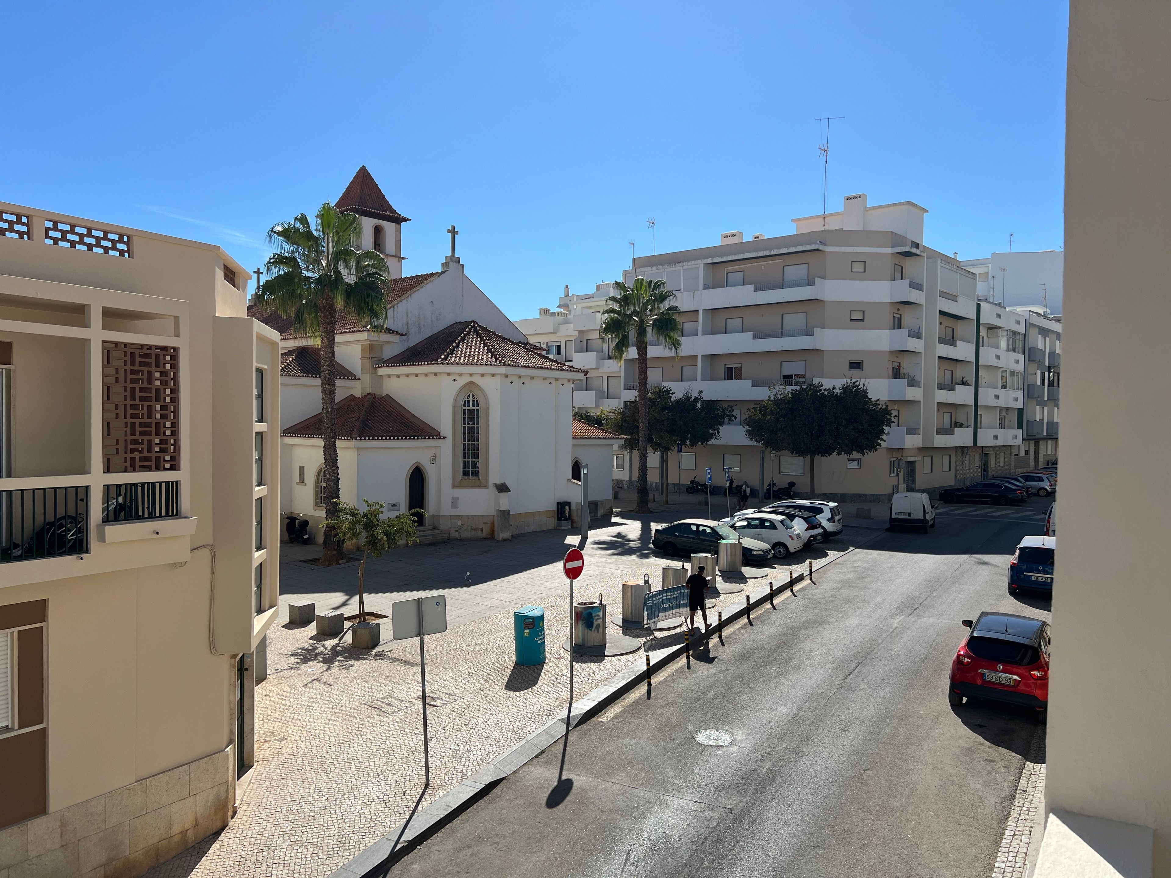 Vista de la calle con una iglesia, coches aparcados y edificios residenciales.
