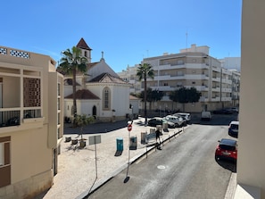 A street view with a church, parked cars, and residential buildings. - Holiday Home 'Apartamento Praia' with Sea View, Wi-Fi and Air Conditioning (Armação de Pêra)