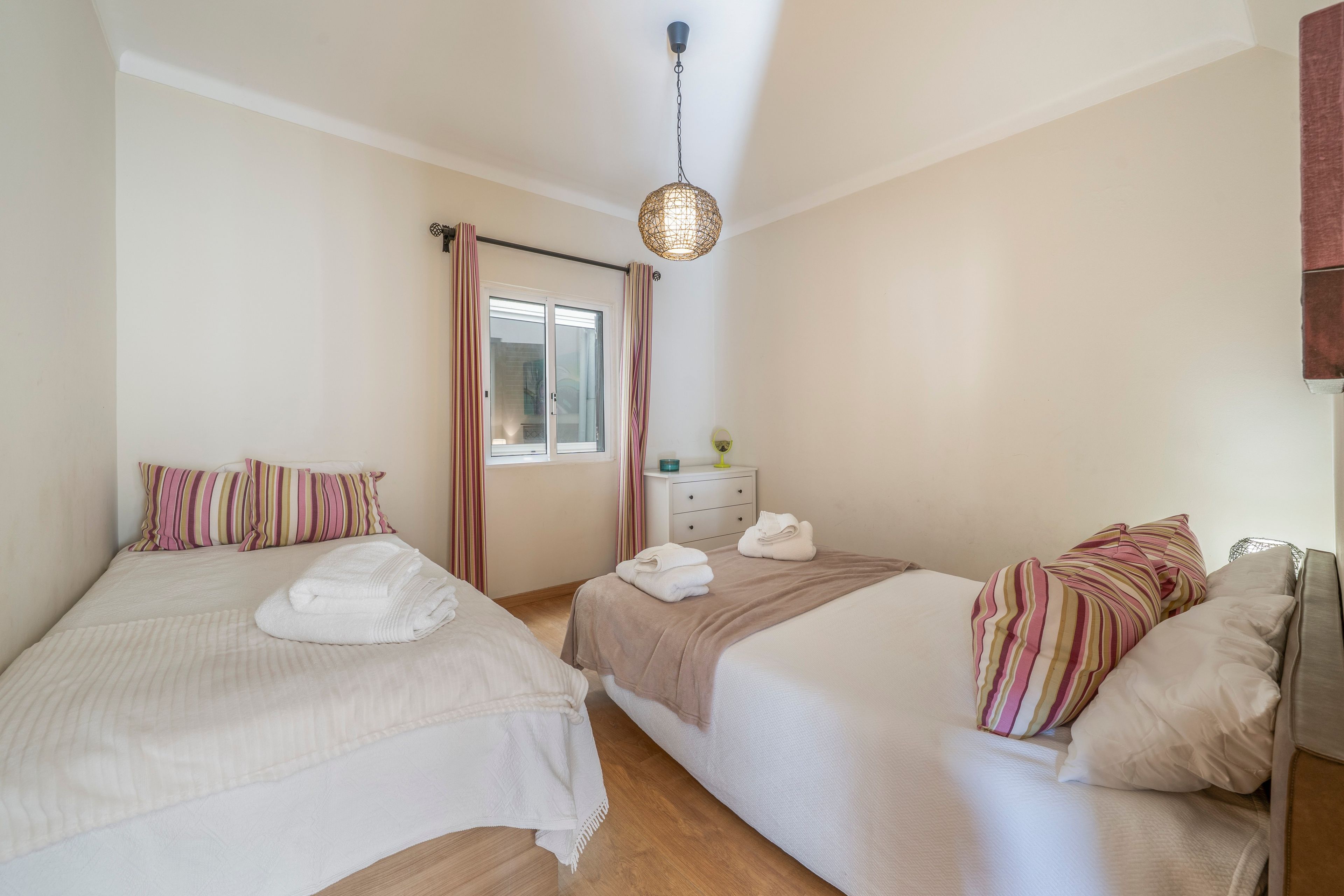 Habitación de hotel con dos camas, cada una con una almohada a rayas y una toalla doblada.