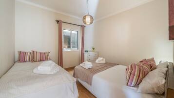 Habitación de hotel con dos camas, cada una con una almohada a rayas y una toalla doblada.