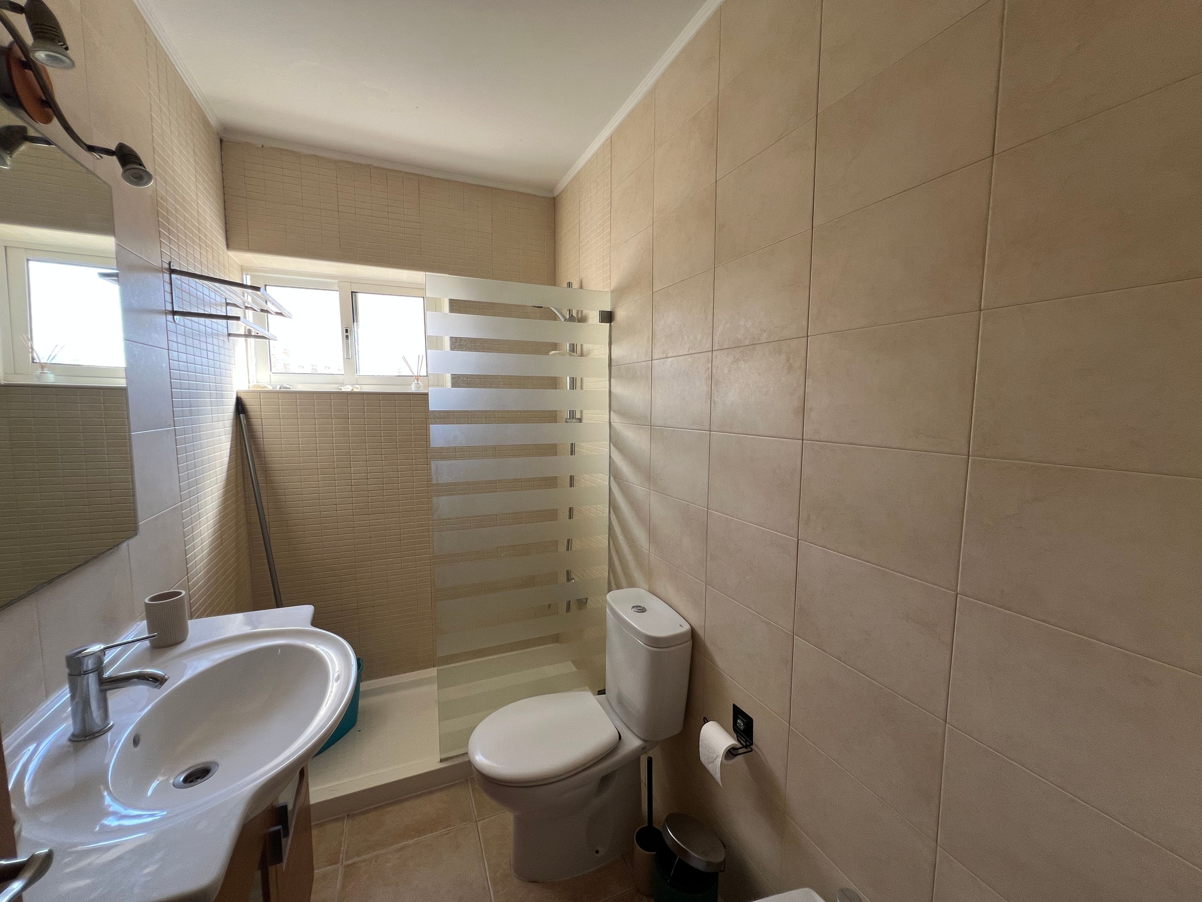 Un baño con lavamanos, inodoro y zona de ducha.