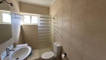 Un baño con lavamanos, inodoro y zona de ducha.