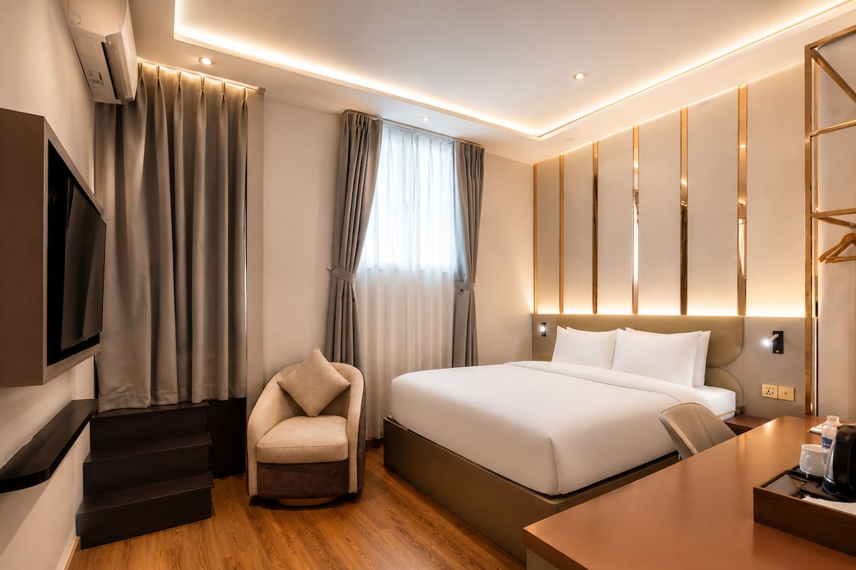 A modern hotel room with a bed, a chair, a desk, and a TV.