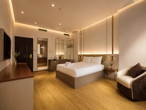 A modern hotel room with a large bed, bedside tables, a seating area, and a bathroom with a mirror and sink. - KAS Dilly Luxury Hotel (Ho Chi Minh)