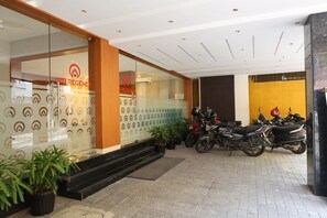 A building entrance with a glass facade, a fire safety sign, and a row of parked motorcycles. - Citi Regency (Chennai)