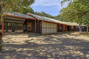 Eine Blockhütte mit überdachter Veranda, Garage und einem eingezäunten Bereich.