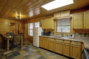 Een houten cabin met een keuken, eethoek en een groot raam.