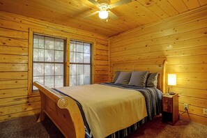 A wooden cabin bedroom with a bed, a nightstand, a lamp, and a ceiling fan. - 2 Mi to Historic Dtwn! Family Getaway w/ Game Room (Granbury)