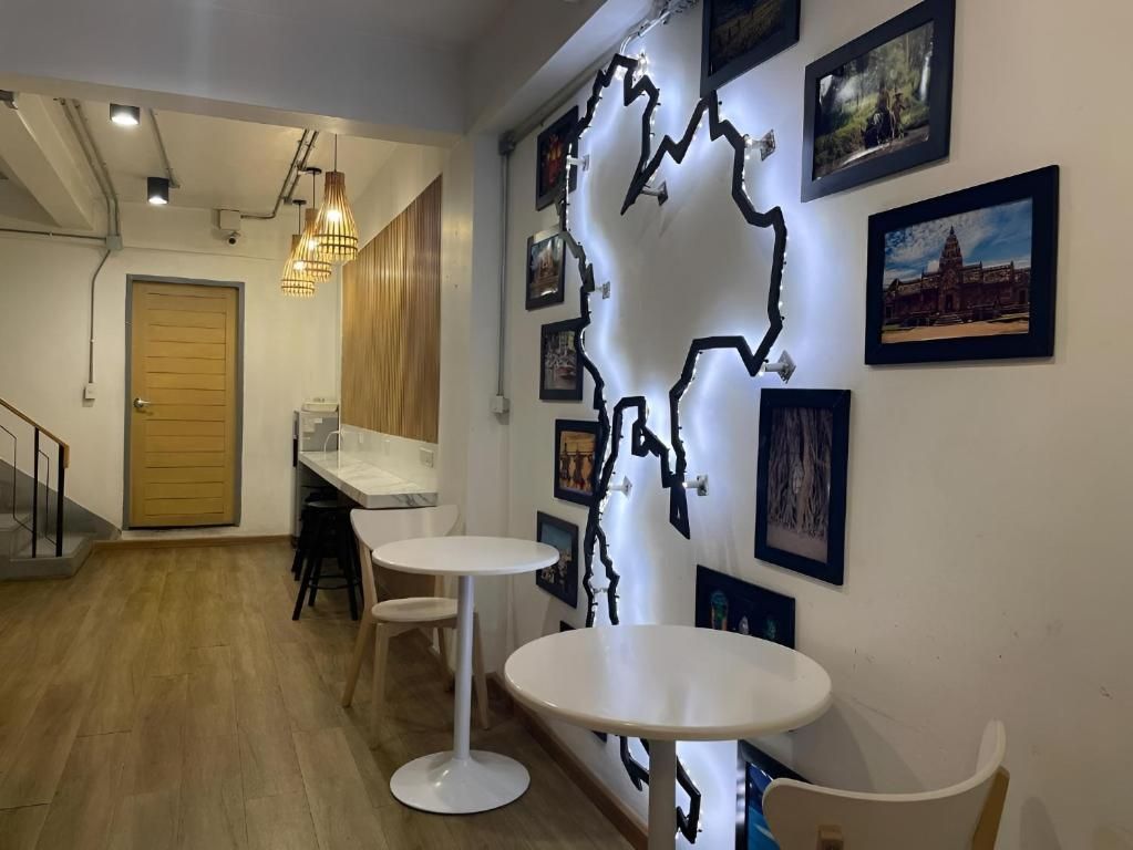 Una habitación con piso de madera, paredes blancas y una mesa blanca con una silla. Hay cuadros en la pared y una puerta de madera.