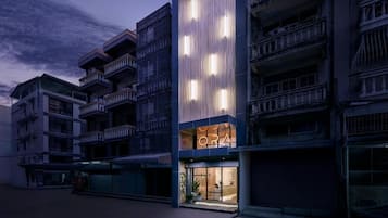 Un edificio moderno con un llamativo letrero 'ORA', varios balcones y un escaparate de vidrio.