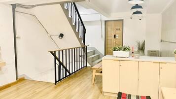 Un interior moderno con una escalera, un armario de madera y una puerta marcada con el número 101.